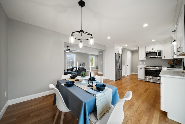 dining area featuring sink, light hardwood / wood-style flooring, and ceiling fan