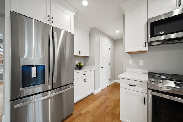 kitchen with appliances with stainless steel finishes, white cabinetry, and light wood-type flooring