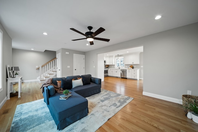 living room with light hardwood / wood-style flooring, sink, and ceiling fan