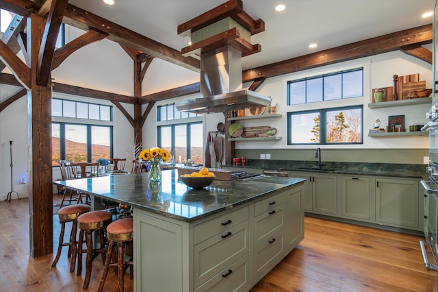 kitchen with green cabinets, sink, island range hood, and light wood-type flooring