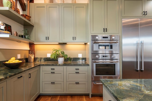 kitchen featuring appliances with stainless steel finishes, light hardwood / wood-style flooring, and dark stone counters