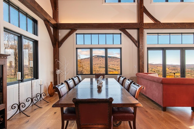 dining space featuring beamed ceiling, a mountain view, high vaulted ceiling, and light wood-type flooring