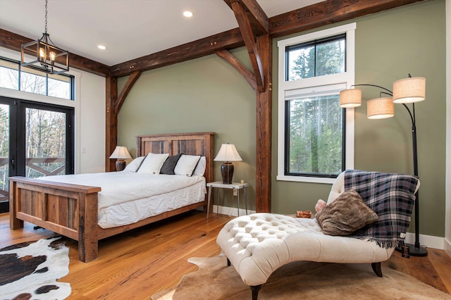 bedroom with light hardwood / wood-style flooring, beam ceiling, and multiple windows