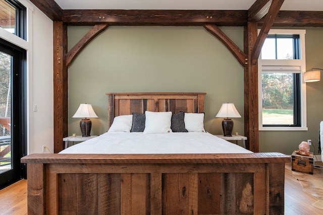 bedroom with beam ceiling and light hardwood / wood-style flooring