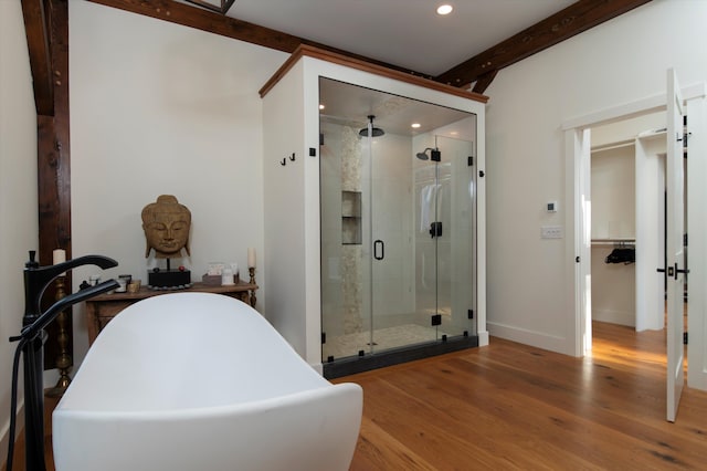 bathroom featuring beamed ceiling, plus walk in shower, and hardwood / wood-style flooring