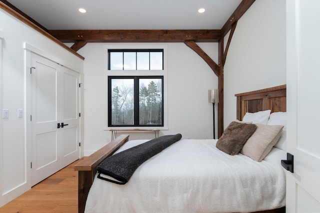 bedroom with beamed ceiling and light hardwood / wood-style flooring