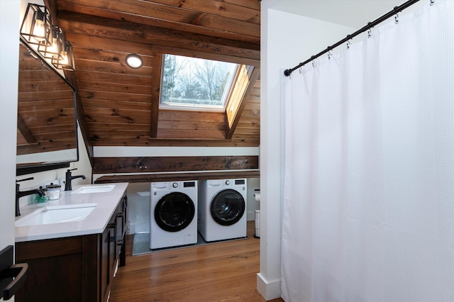 laundry room featuring a skylight, sink, wood-type flooring, and washing machine and dryer