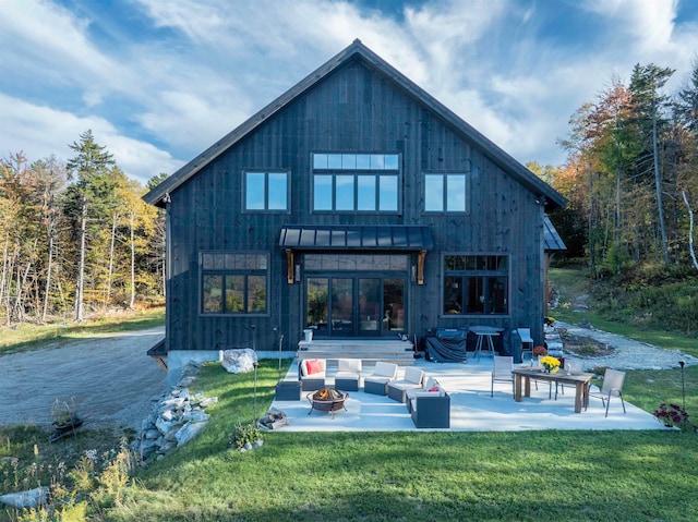 rear view of house with a patio, a lawn, and a fire pit