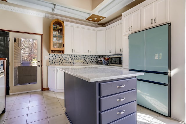 kitchen with stainless steel fridge, a center island, white cabinets, and backsplash