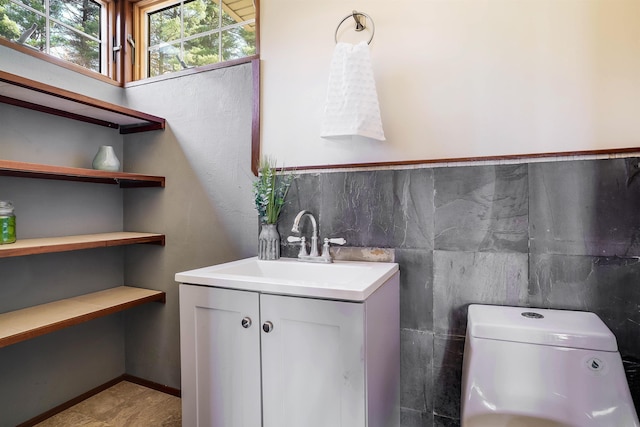 bathroom with vanity, toilet, tile walls, and tile patterned flooring