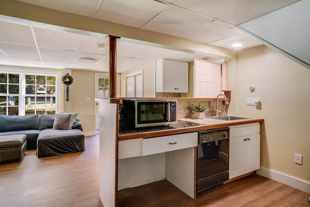 kitchen featuring black dishwasher, light hardwood / wood-style flooring, and white cabinets