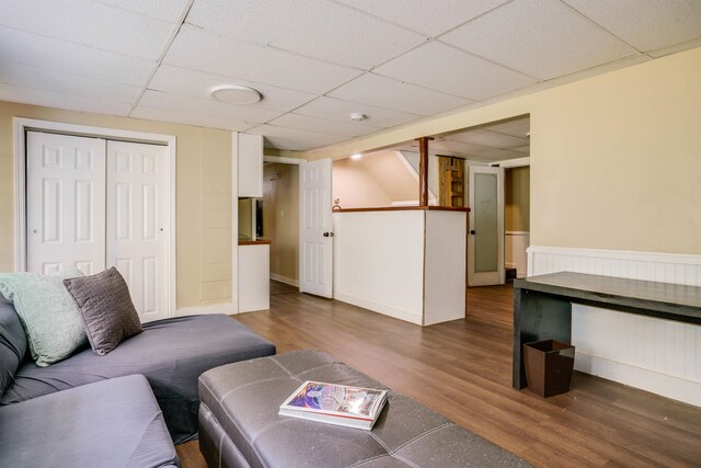 living room with dark hardwood / wood-style floors and a paneled ceiling