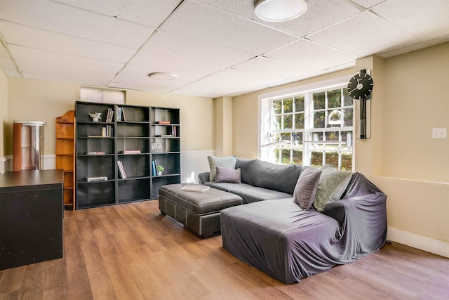 living room with wood-type flooring and a drop ceiling