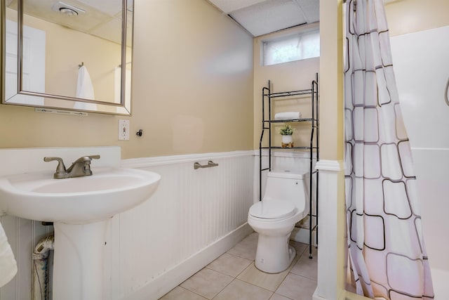 bathroom with sink, a paneled ceiling, toilet, and tile patterned flooring