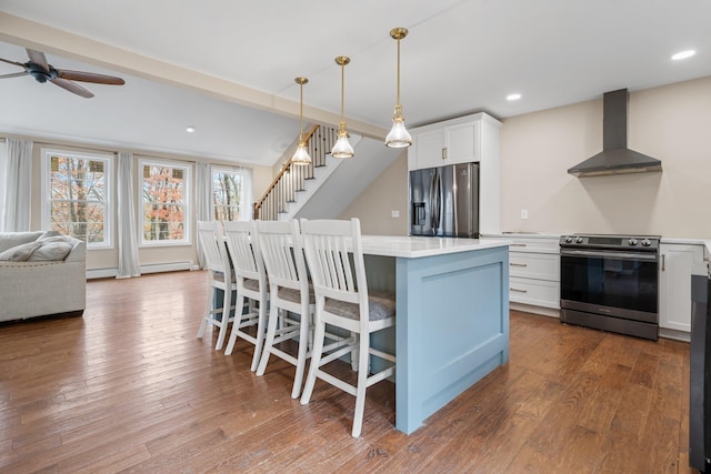 155 E Shore Dr, Weare, NH 03281 - kitchen with wall chimney range hood, stainless steel appliances, white cabinetry, a ceiling fan, and a center island