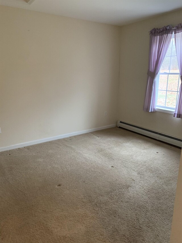 carpeted empty room featuring a baseboard heating unit