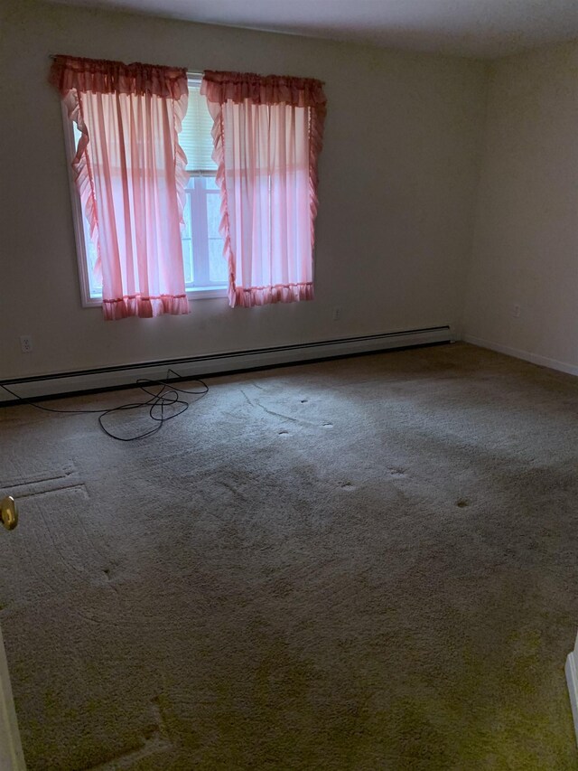 unfurnished room with carpet and a baseboard heating unit