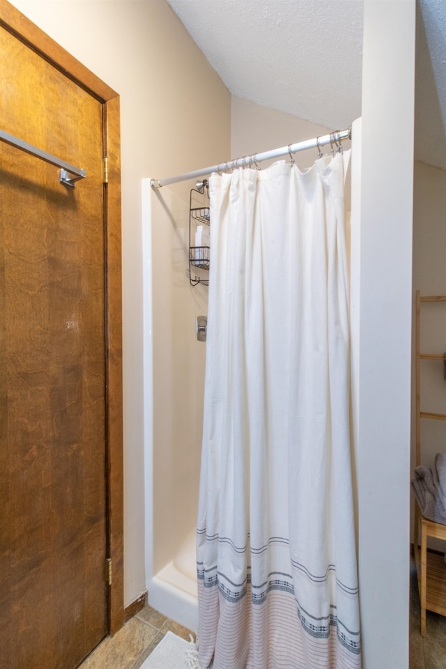 bathroom with a textured ceiling, walk in shower, and tile patterned flooring