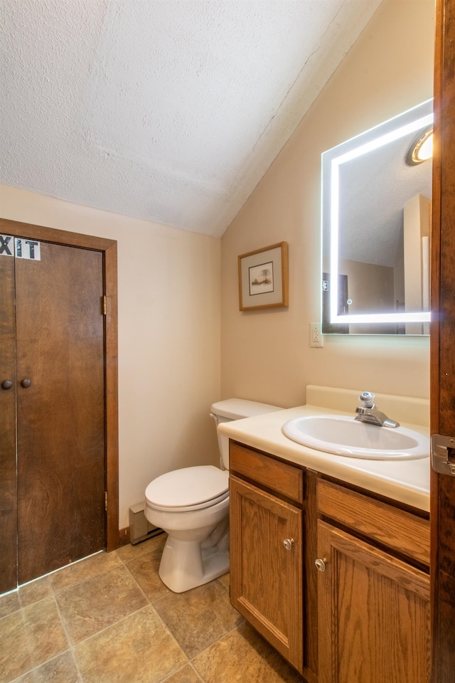 bathroom featuring vanity, toilet, a textured ceiling, and vaulted ceiling