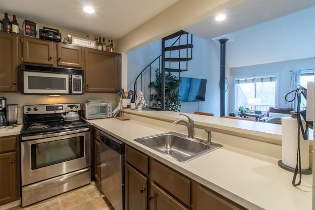 kitchen featuring kitchen peninsula, sink, pendant lighting, dark brown cabinetry, and stainless steel appliances