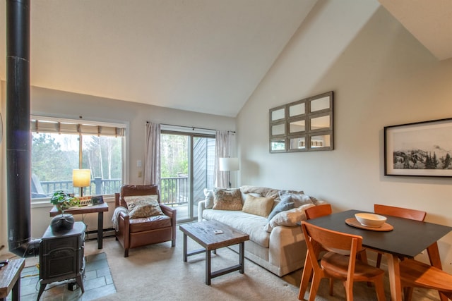 carpeted living room featuring high vaulted ceiling, a wood stove, and a baseboard heating unit