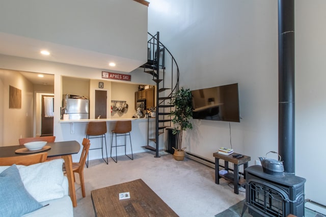 carpeted living room with a wood stove and a baseboard heating unit