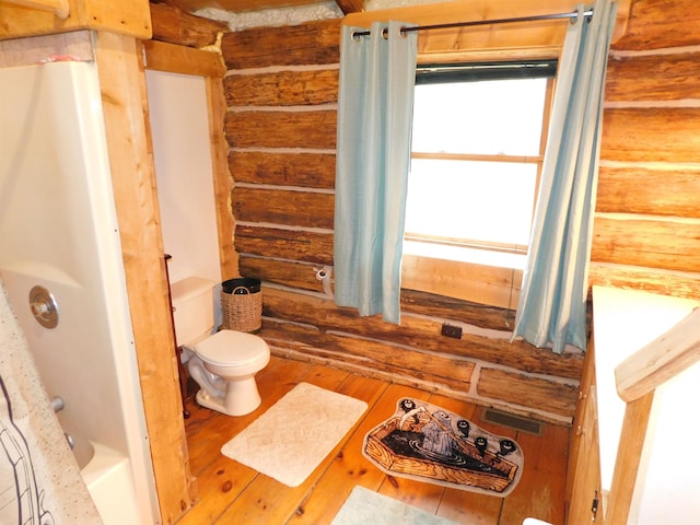 bathroom with wood-type flooring, toilet, log walls, and shower / bath combination with curtain