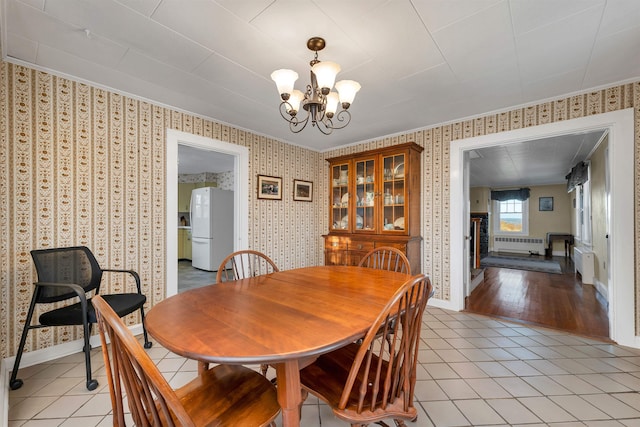 dining room featuring radiator heating unit, light hardwood / wood-style flooring, and a notable chandelier