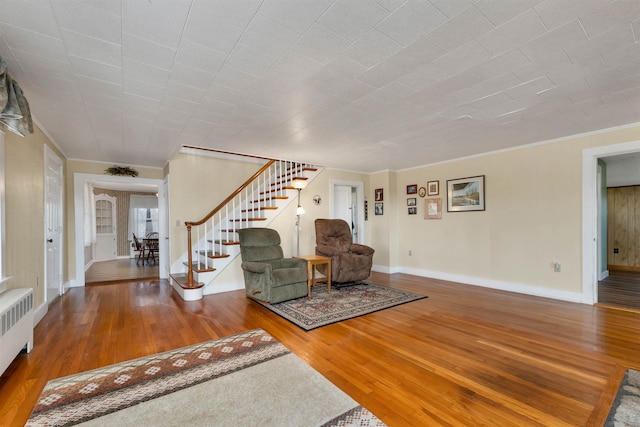 unfurnished living room with ornamental molding, radiator heating unit, and wood-type flooring