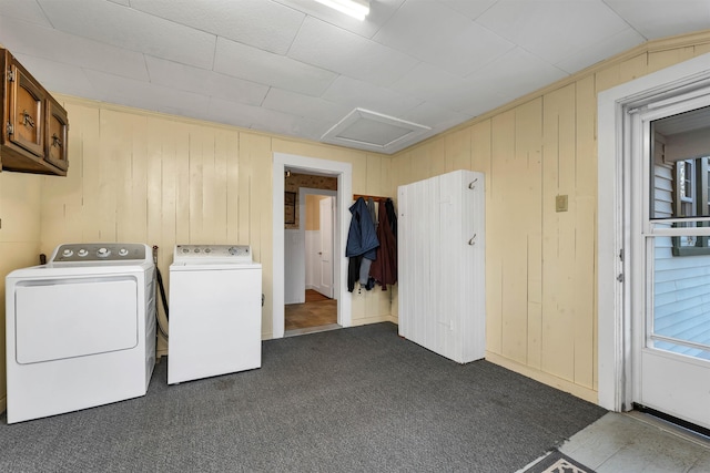 laundry area with dark colored carpet, washer and clothes dryer, wooden walls, and cabinets