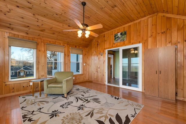 living area featuring wood walls, light wood-type flooring, and vaulted ceiling