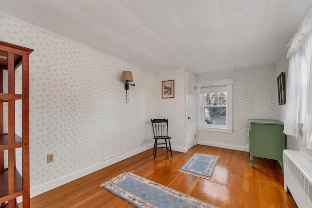 sitting room featuring wood-type flooring, crown molding, and radiator