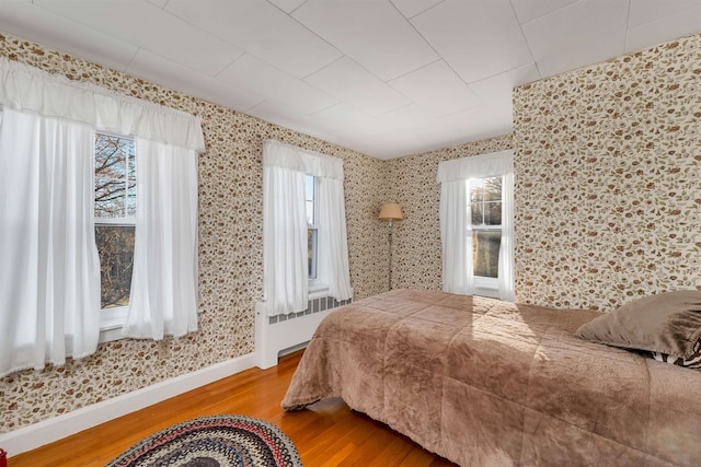 bedroom with radiator heating unit and wood-type flooring