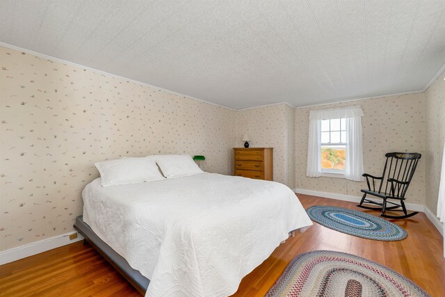 bedroom featuring a textured ceiling, hardwood / wood-style flooring, and ornamental molding