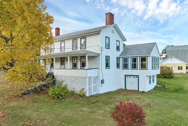 rear view of property featuring a garage, a yard, and a porch