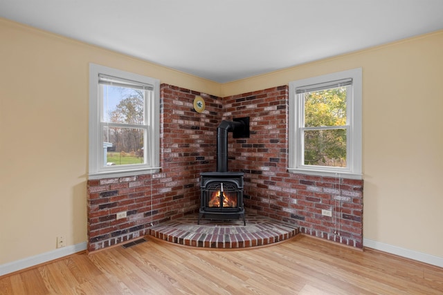 room details with hardwood / wood-style floors, a wood stove, and ornamental molding