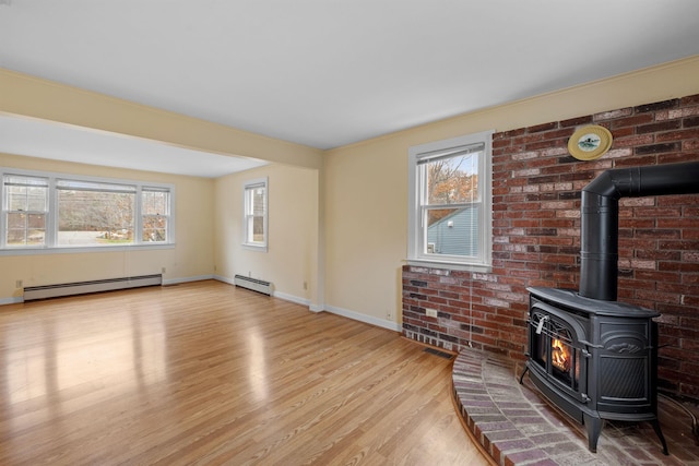 unfurnished living room with a wood stove, a healthy amount of sunlight, and a baseboard radiator