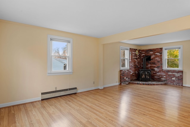 unfurnished living room with a wood stove, light hardwood / wood-style floors, and a baseboard radiator