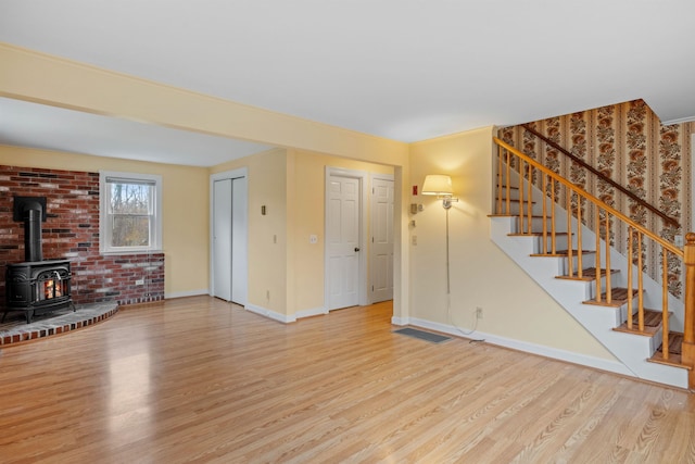 unfurnished living room featuring light wood-type flooring and a wood stove