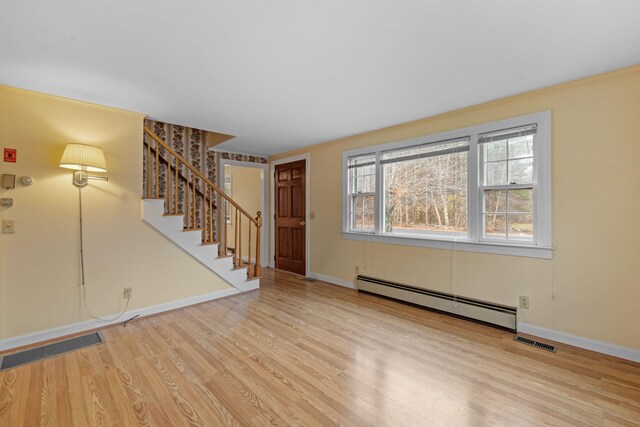 unfurnished living room with a baseboard heating unit and light wood-type flooring