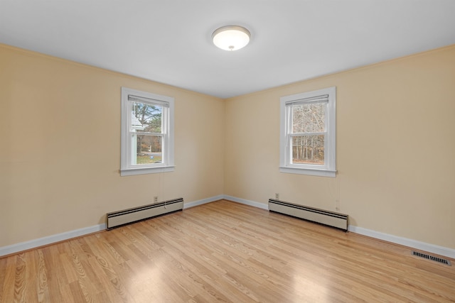 empty room featuring a baseboard radiator and light wood-type flooring