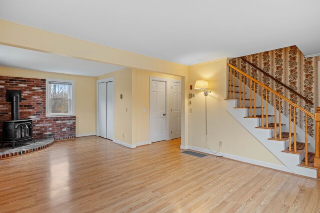 unfurnished living room featuring a wood stove and light hardwood / wood-style floors