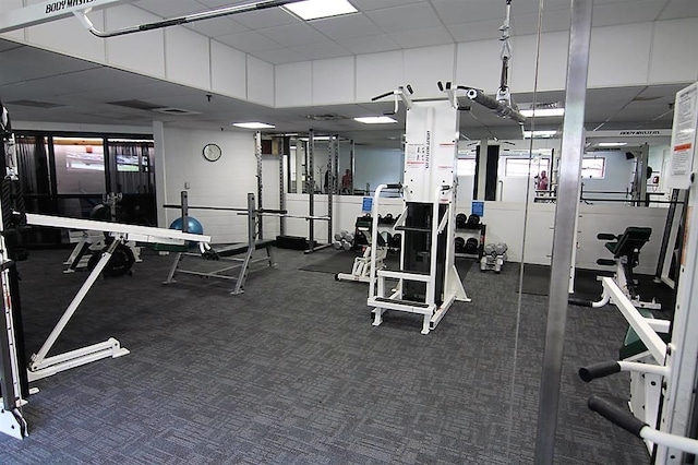 exercise room featuring a drop ceiling and dark carpet