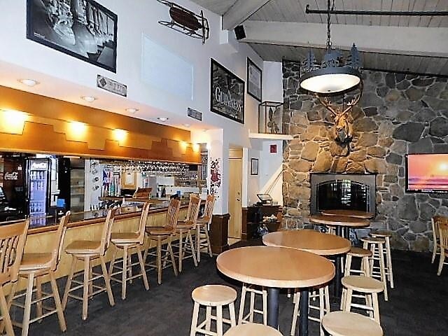 dining area featuring a high ceiling, bar area, and beam ceiling