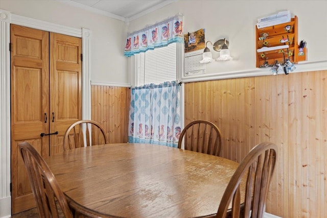 dining area with ornamental molding and wood walls