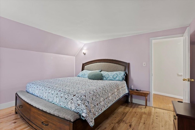 bedroom featuring light hardwood / wood-style floors and lofted ceiling