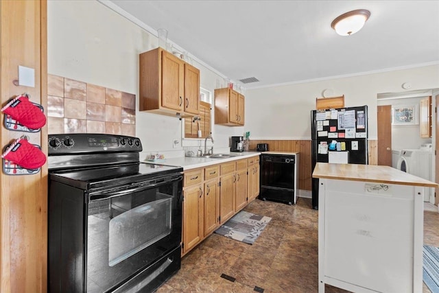 kitchen featuring black appliances, ornamental molding, separate washer and dryer, wooden walls, and sink