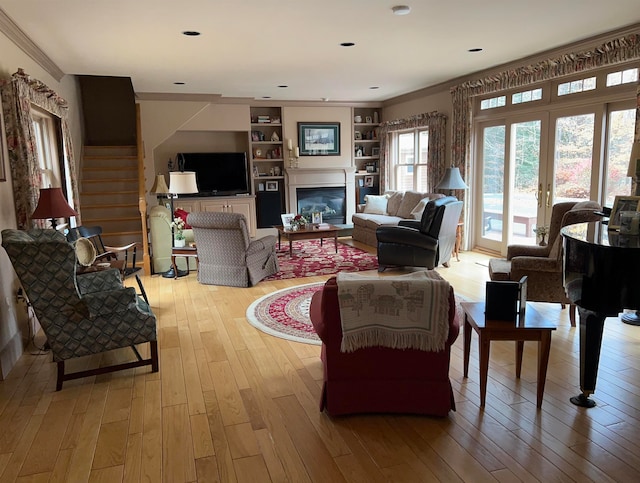 living room featuring light hardwood / wood-style flooring, crown molding, and built in features