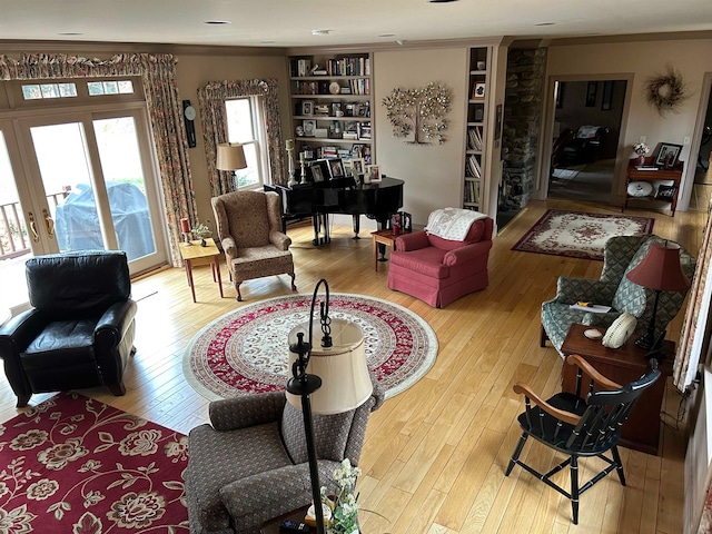 living room with french doors, light hardwood / wood-style flooring, crown molding, and built in features