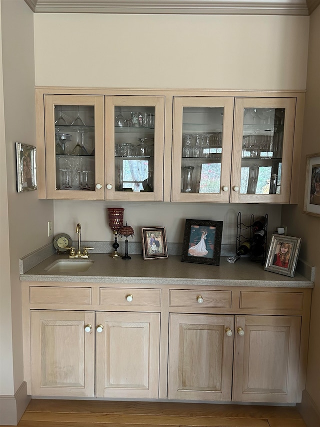 bar with light wood-type flooring, sink, and crown molding